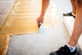 Worker adding glue on cement floor, preparing surface for wood parquet
