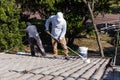 Worker adding undercoat foundation paint onto rooftop with roller at residential building in renovation
