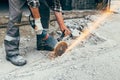 A worker with an angle grinder cuts the concrete pavement of the road, and sparks fly. Royalty Free Stock Photo