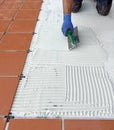 The worker applies the glue to a tile on a concrete floor