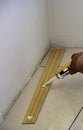 Worker applies glue on wooden skirting