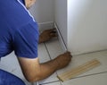 Worker applies glue on wooden skirting board