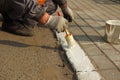 Worker applies white paint markings on the curb. profession urban service