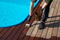 Worker applying brown wood protection oil on decking boards with paint brush next to the pool. Copy space Royalty Free Stock Photo