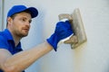 Worker applying decorative facade plaster on house wall