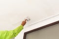 A worker applying plaster with a putty knife to smooth a ceiling surface. Royalty Free Stock Photo
