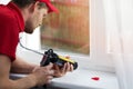 Worker applying silicone sealant under window frame