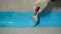 A worker is applying waterproofing paint to the floor in the bathroom. The process of applying waterproofing in the Royalty Free Stock Photo