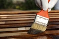 Worker applying wood stain onto planks, closeup. Space for text