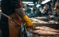 Worker in apron and gloves sorting fresh fish at a seafood processing plant, illuminated interior. Royalty Free Stock Photo
