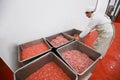 A worker arranged boxes with raw meat minced in an industrial process factory in a steel crate at a processing Royalty Free Stock Photo