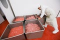 A worker arranged meat minced in an industrial process in a stainless steel crate at a meat processing factory.