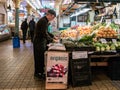 Worker arranges organic produce at Pike Place Public Market, Sea