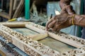 worker assembling a handcarved wooden frame for a mirror