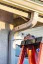 Worker Attaching Aluminum Rain Gutter and Down Spout to Fascia of House Royalty Free Stock Photo