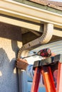 Worker Attaching Aluminum Rain Gutter and Down Spout to Fascia of House Royalty Free Stock Photo