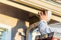 Worker Attaching Aluminum Rain Gutter and Down Spout to Fascia of House Royalty Free Stock Photo