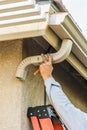 Worker Attaching Aluminum Rain Gutter and Down Spout to Fascia of House Royalty Free Stock Photo