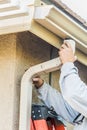 Worker Attaching Aluminum Rain Gutter and Down Spout to Fascia of House