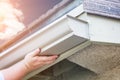 Worker Attaching Aluminum Rain Gutter to Fascia of House