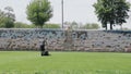 Worker back to camera going and cutting grass using mower, cropper or mowing-machine on the stadium