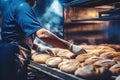 A worker in a bakery puts bread in the oven. Bread production enterprise. Bakery. Close-up