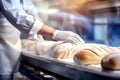 A worker at a bakery takes fresh bread out of the oven. Industrial production