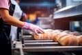 A worker at a bakery takes fresh bread out of the oven. Industrial production