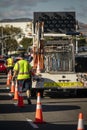 Worker behind utility truck placing bright orange traffic cones on roadway f Royalty Free Stock Photo