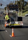 Worker behind utility truck placing bright orange traffic cones on roadway f Royalty Free Stock Photo