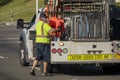 Worker behind utility truck placing bright orange traffic cones on roadway for traffic control