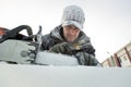 Worker in a black cap covered with frost sharpening a chainsaw chain