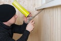 Worker in a black hat, makes thermal insulation with mounting foam