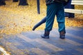 Worker blowing fallen yellow leaves from sidewalk using backpack leaf blower Royalty Free Stock Photo