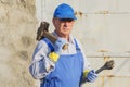 Worker in blue overalls with a sledgehammer and a wrench. Serious look. Royalty Free Stock Photo