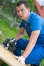 A worker in a blue uniform, cuts a wooden Board with an electric saw, close-up