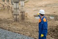 A worker in a blue uniform and a white helmet shows the developer at the stage of construction of the Foundation for the house Royalty Free Stock Photo