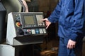 Worker in blue workwear holds hands on the control panel of the CNC machine. Close-up Royalty Free Stock Photo