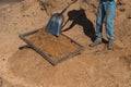 Worker of a brick factory strains sand with a  in a wheelbarrow, for the elaboration of bricks Royalty Free Stock Photo