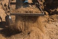 Worker of a brick factory strains sand with a  in a wheelbarrow, for the elaboration of bricks Royalty Free Stock Photo