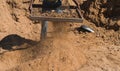 Worker of a brick factory strains sand with a  in a wheelbarrow, for the elaboration of bricks Royalty Free Stock Photo