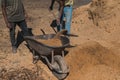 Worker of a brick factory strains sand with a  in a wheelbarrow, for the elaboration of bricks Royalty Free Stock Photo