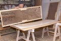 Worker in carpentry lines up glued wooden profiles before pressing in the large clamp machine