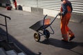 The worker carries the cart. Road repair. The loader is dragging the broken asphalt in a one-wheeled cart.