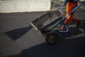 The worker carries the cart. Road repair. The loader is dragging the broken asphalt in a one-wheeled cart.