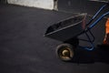 The worker carries the cart. Road repair. The loader is dragging the broken asphalt in a one-wheeled cart.