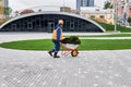 Worker carries turf in a wheelbarrow on the background of urban landscaping