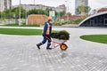 Worker carries turf in a wheelbarrow on the background of urban landscaping