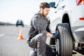 Worker changing car wheel on the highway Royalty Free Stock Photo