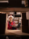 Worker checking inventory using Laptop Computer. Young female Santa Claus working in a warehouse with rows of shelves Royalty Free Stock Photo
